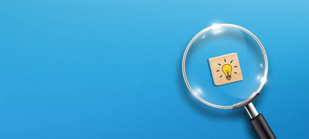 istock Creative idea concept, magnifying glass and light bulb icon on wooden block with blue background 1340700490