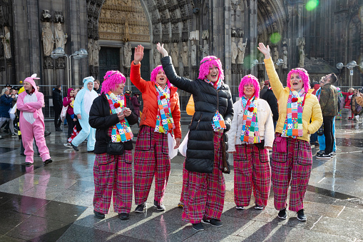 Cologne, Germany - February 20, 2020: Group of women, wearing colorful costumes and pink wigs on Weiberfastnacht, Old Wives Day, celebrating in front of the cathedral of Cologne, corona virus started to spread in Germany, but most of the people are non yet aware of it