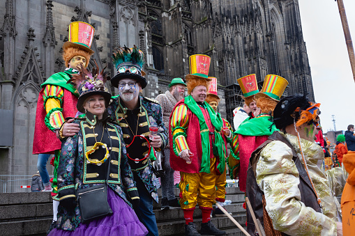 Cologne, Germany - February 20, 2020: Group of adults, wearing colorful costumes on Weiberfastnacht, Old Wives Day, celebrating in front of the cathedral of Cologne, corona virus started to spread in Germany, but most of the people are non yet aware of it