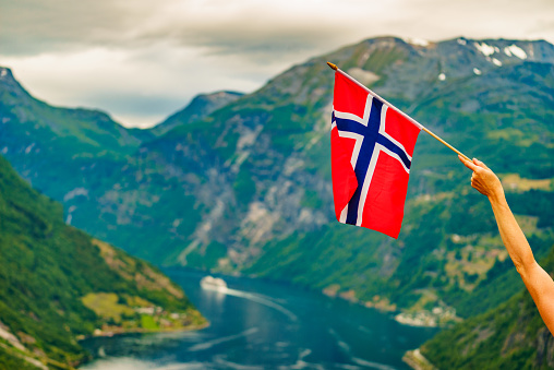 Norwegian flag and view over Geirangerfjord from Flydalsjuvet viewing point. Tourist attraction. Tourism vacation and travel.