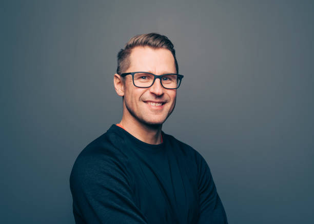 istock Adult confident man smiling at camera standing against dark wall 1340703531