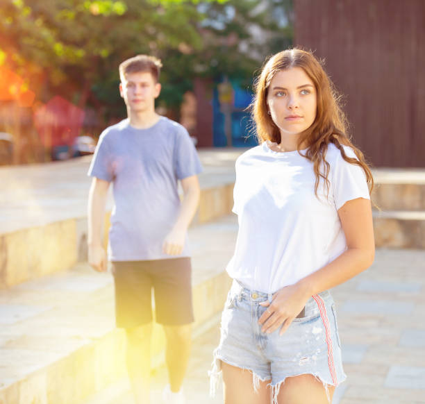 istock Girl is standing and guy is walking behind her 1340706891