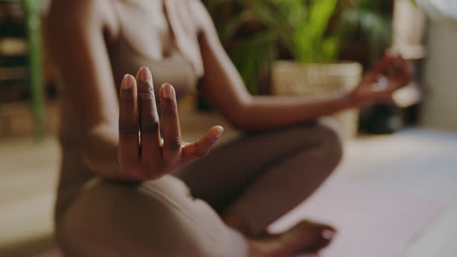 4k video footage of an unrecognizable woman meditating in the lotus position at home