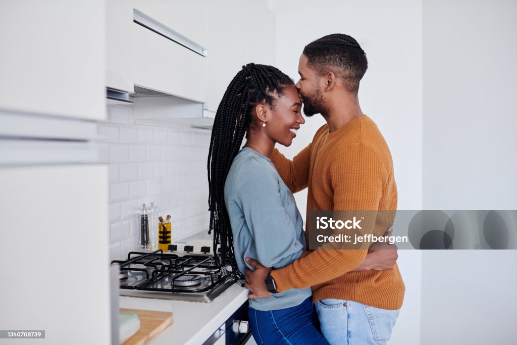 Shot of a young couple being affectionate in the kitchen together at home the object of my affection Forehead Stock Photo