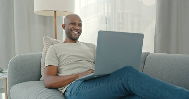 istock Shot of a young man using a laptop while sitting on the couch at home 1340709145