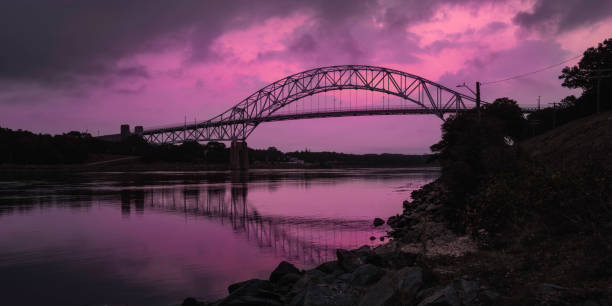 istock Dramatic stormy cloudscape over the arching bridge at pink-colored sunrise at Sagamore Bridge riverbank 1340712665