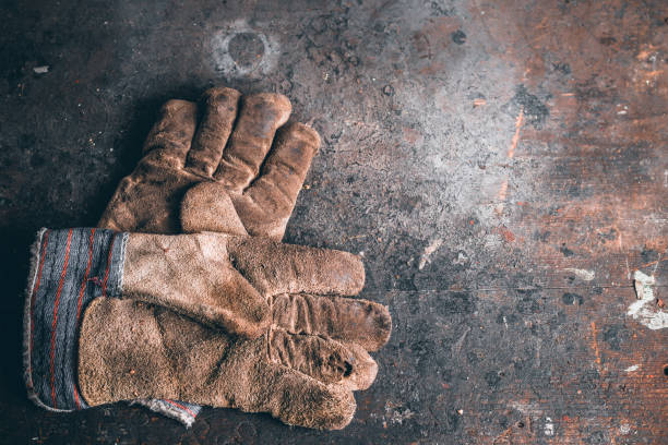 ein paar schutzarbeitshandschuhe auf holzerner werkbank. - arbeitshandschuh stock-fotos und bilder