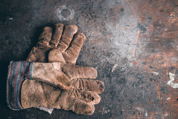 un paio di guanti da lavoro di protezione su banco da lavoro in legno. - work glove immagine foto e immagini stock