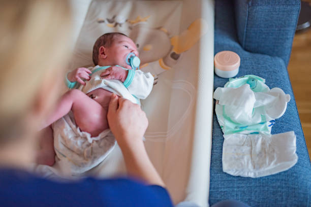 Mother changing diaper to her newborn baby. stock photo