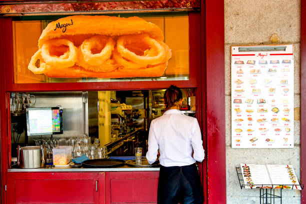 A food server waiting for her order to deliver to customers at an outdoor eating establishment in Madrid. Spain.
