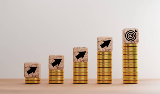 istock Up arrow and target board print screen on wooden cube block which lay down on increasing golden coin stacking for Business achievement goal and objective target concept by 3d render. 1340716319