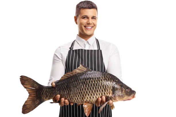 istock Youn man wearing apron and holding a big carp fish 1340717619
