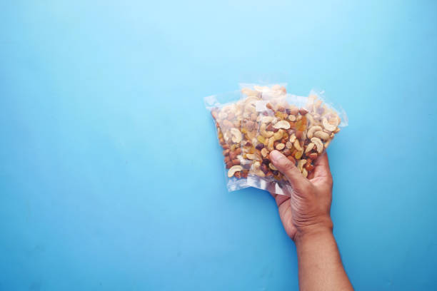 istock hand hold a packet of mixed nuts on blue background 1340718945