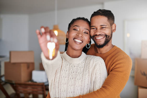 Shot of a young couple hugging while showing their new house keys at home Can you tell how happy we are? home ownership stock pictures, royalty-free photos & images