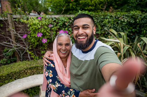Pakistani grandson and grandmother taking a selfie together in a garden in Middlesbourgh, North East of England.