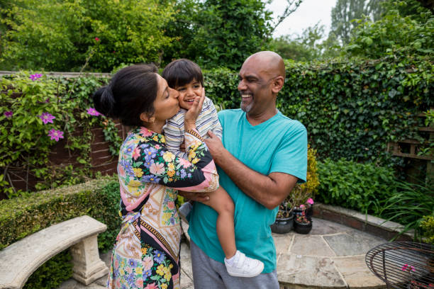 Loving Grandparents Pakistani grandparents with their grandsons standing in an outdoor garden. They are in the Northeast of England in summer and the grandmother is kissing the young boy. cleveland england stock pictures, royalty-free photos & images