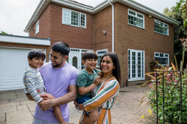 The Happiest Family Parents holding their two sons standing in front of their modern home in Middlesborough, Northeast of England in summer. They are all looking at the camera laughing. middlesbrough stock pictures, royalty-free photos & images