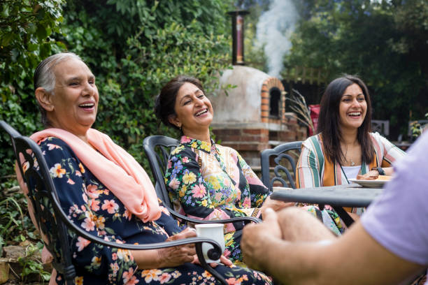Family Laughing Together Asian/Pakistani multi generation family sitting around a table in a garden in Middlesbourgh, North East of England. pakistani ethnicity stock pictures, royalty-free photos & images