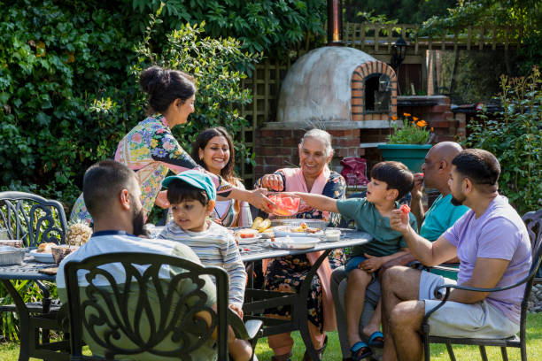 Spending Time as a Family Asian/Pakistani multi generation family sitting around a table in a garden in Middlesbourgh, North East of England. outdoor dining photos stock pictures, royalty-free photos & images