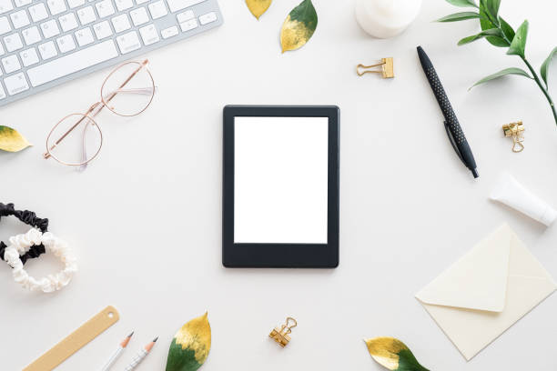 istock E-reader mockup on stylish home office desk table. Flat lay, top view feminine workspace with computer keyboard, glasses, e-book, accessories. 1340720876