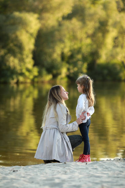 istock Mother and daughter walk on beach near river. 1340721423