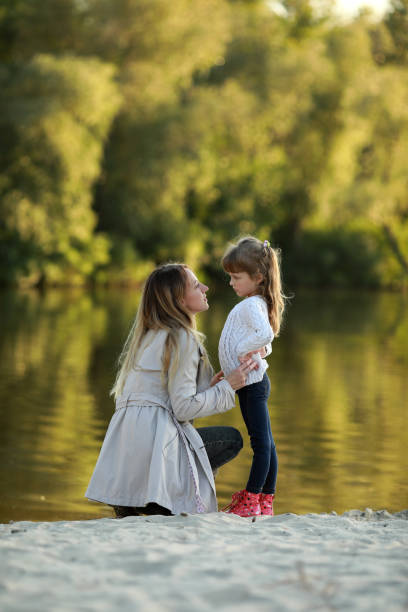 istock Mother and daughter walk on beach near river. 1340721439