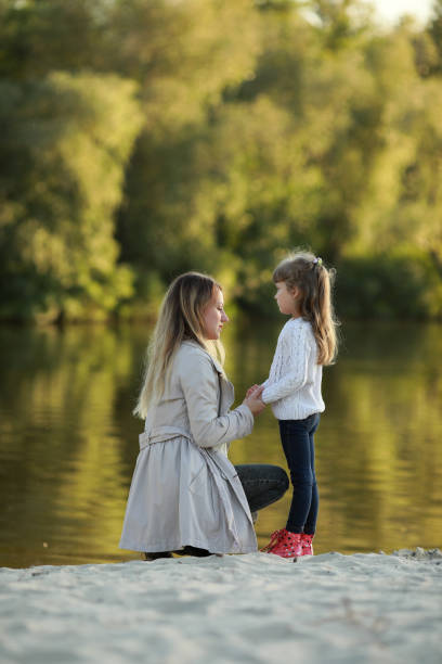 istock Mother and daughter walk on beach near river. 1340721456