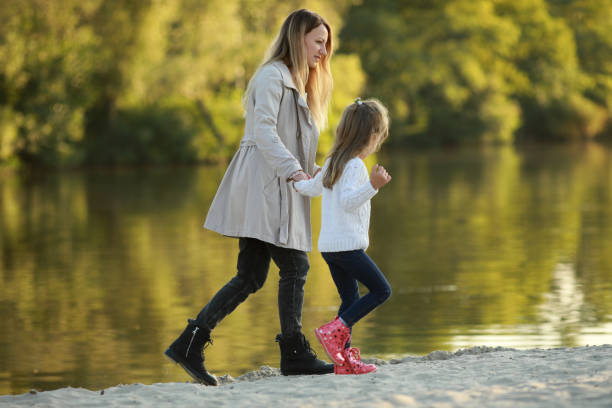 istock Mother and daughter walk on beach near river. 1340721477