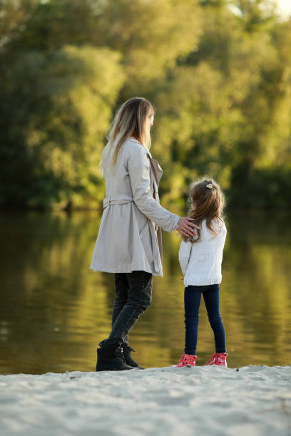 istock Mother and daughter walk on beach near river. 1340721496