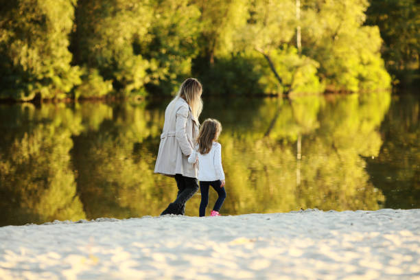 istock Mother and daughter walk on beach near river. 1340721586
