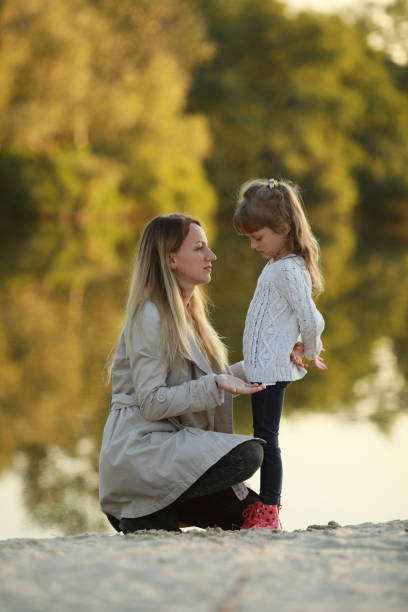 istock Mother and daughter walk on beach near river. 1340722336