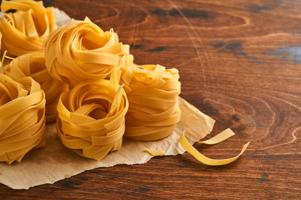 homemade tagliatelle pasta in brown paper on an old wooden background. - cooking oil olive oil nutritional supplement spoon imagens e fotografias de stock