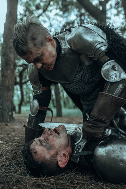 istock Medieval knight bends over lying enemy and puts a dagger to his throat. 1340723495