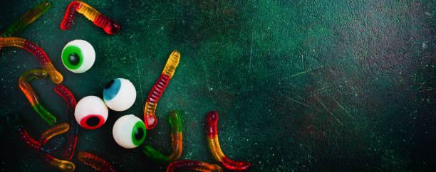 Halloween marshmallow colored eyes on a dark green old concrete background. Top view.