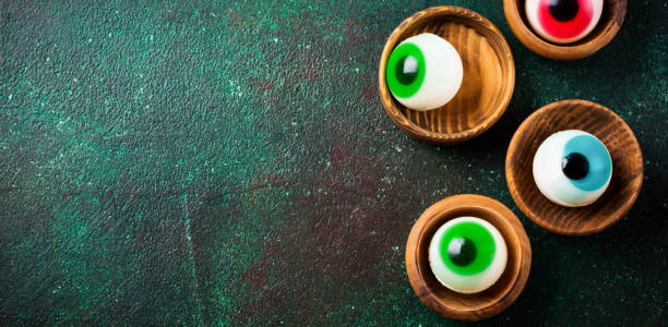 Halloween marshmallow colored eyes on a dark green old concrete background. Top view.
