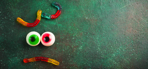 Halloween marshmallow colored eyes on a dark green old concrete background. Top view.
