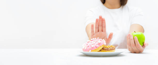 istock Woman on a diet refusing donuts to choose a fresh apple 1340730487