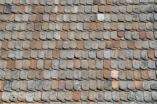 Close up old background tiled roof of a house, Europe. View with details.