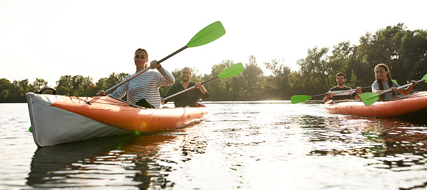 Adventurous young people having fun, kayaking together on a river, spending weekend outdoors on a summer day. Kayaking, travel, leisure concept