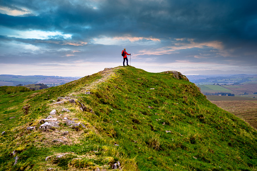 Woman cresting a summit on Hadrian's Wall in the Northumberland region of the United Kingdom. This section is between Walltown and Housesteads.