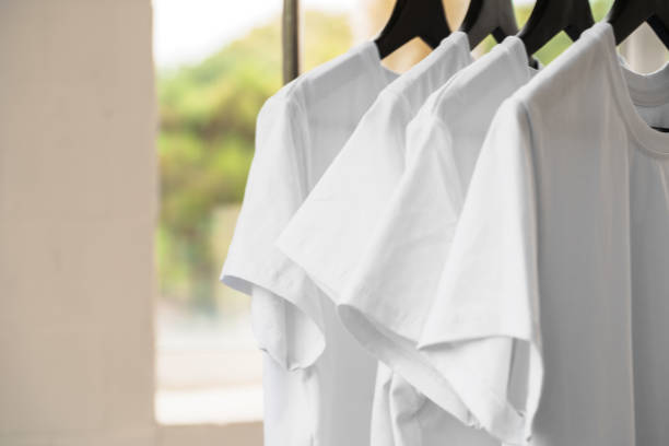 istock Row of white t-shirts on hangers on rack 1340734620