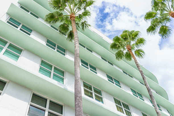 Miami Beach, Florida colorful pastel green house apartment building with Art Deco district style architecture looking up on palm trees and windows stock photo