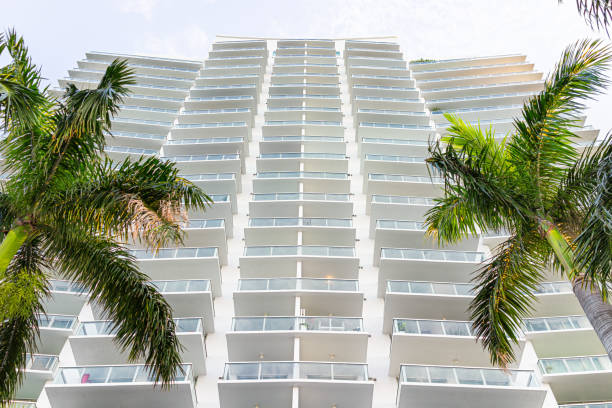 miami beach florida vista de ángulo bajo mirando hacia arriba abstracto en el edificio del complejo de condominios de apartamentos residenciales con muchos balcones de vidrio y palmeras - apartment architecture contemporary beach fotografías e imágenes de stock