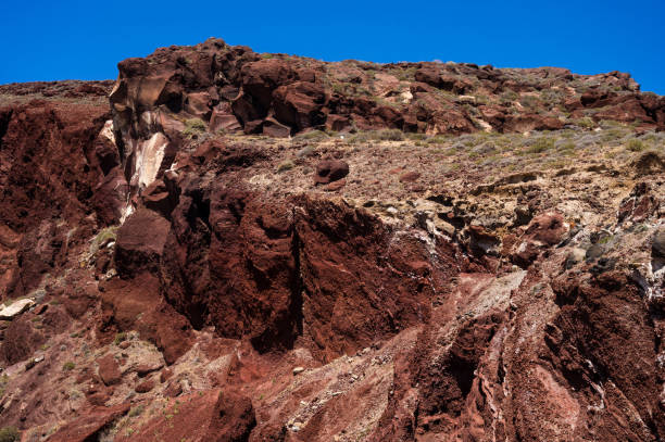 istock Huge red rock cliff on red sand beach Santorini. Alien landscape. 1340738320