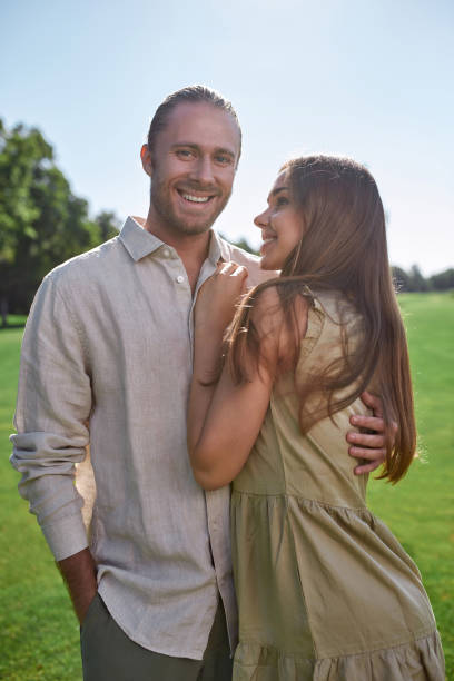 istock Cheerful young couple embracing each other, posing together outdoors while standing in the park 1340738707