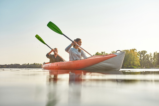 Young woman kayaking together with her boyfriend in a river on a summer day. Kayaking, travel, leisure concept