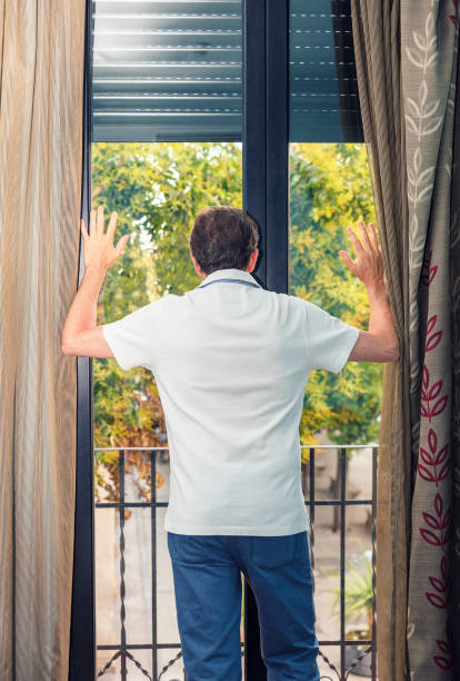 istock man with his back against the window pane looking outside 1340747259