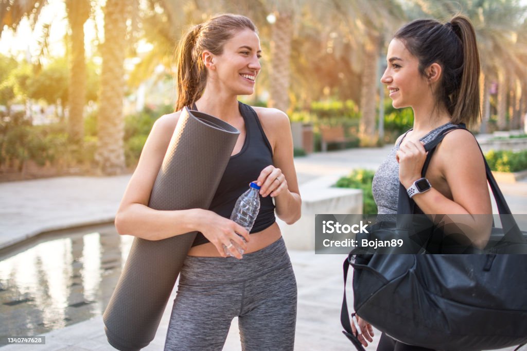 Two Beautiful Fitness Female Friends In Sportswear Holding Gym Bag Yoga Mat  And Water Bottle Talking In The Park Sporty Girl Ready For Training Stock  Photo - Download Image Now - iStock
