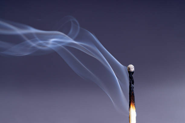 Smoke coming from an extinguished match against a dark purple background
