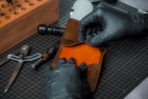 a tailor performs quality control of wallet manufacturing products